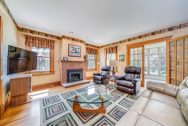 living room featuring a brick fireplace and light wood-type flooring