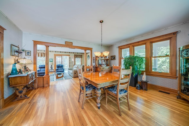 dining space with a wealth of natural light, light hardwood / wood-style flooring, and an inviting chandelier