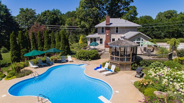 view of swimming pool featuring a diving board, a gazebo, area for grilling, a patio area, and a deck