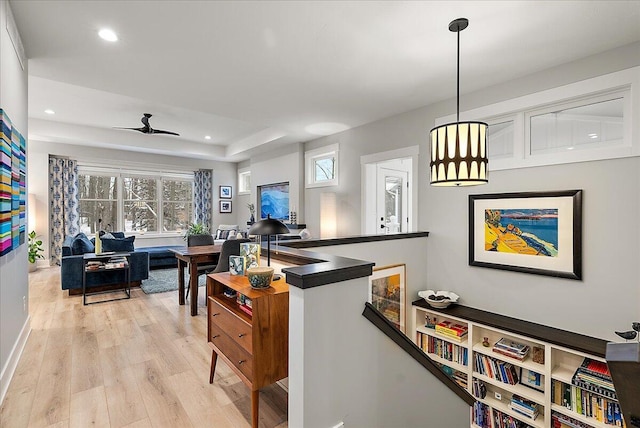 kitchen with light wood-type flooring, decorative light fixtures, a raised ceiling, and ceiling fan