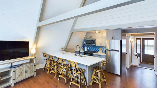 kitchen featuring a kitchen breakfast bar, sink, dark hardwood / wood-style floors, tasteful backsplash, and stainless steel appliances