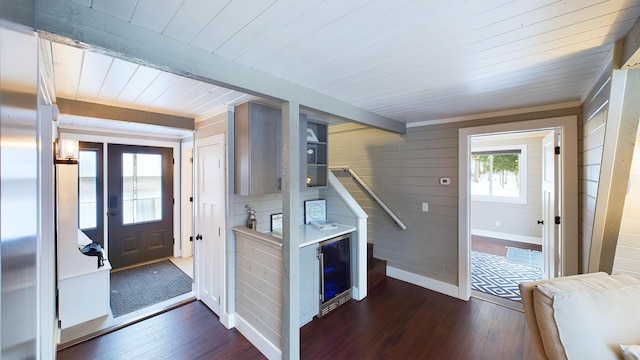 entrance foyer featuring wood walls, beam ceiling, and dark hardwood / wood-style flooring