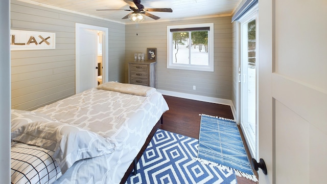 bedroom with crown molding, ceiling fan, dark wood-type flooring, and wood walls