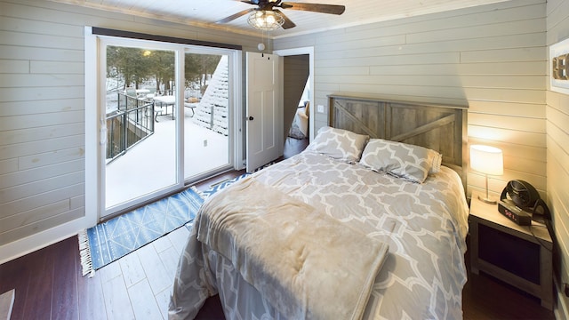 bedroom featuring access to outside, ceiling fan, wooden walls, and dark hardwood / wood-style floors