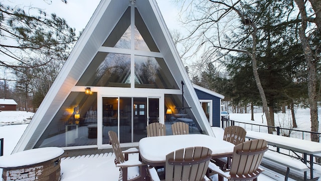 snow covered house featuring a sunroom