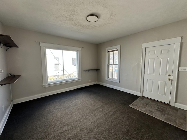 unfurnished living room with dark carpet and a textured ceiling