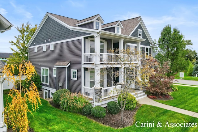 view of front of property featuring a porch, a front lawn, a shingled roof, and a balcony