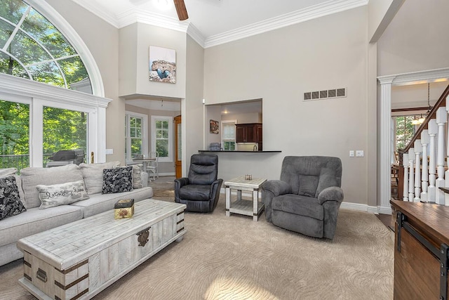 living room with ceiling fan, plenty of natural light, light colored carpet, and ornamental molding