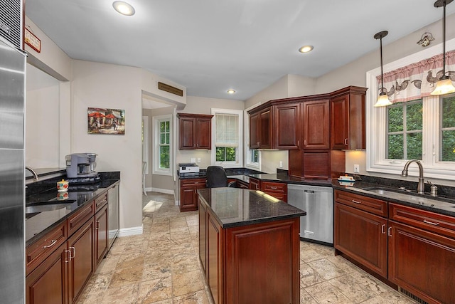 kitchen with hanging light fixtures, sink, appliances with stainless steel finishes, and dark stone counters