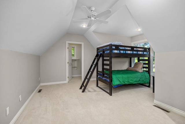 bedroom featuring ceiling fan, light colored carpet, vaulted ceiling, and a spacious closet