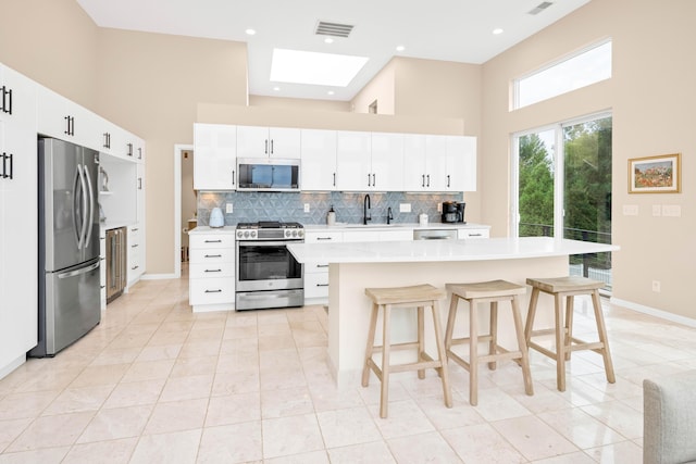 kitchen featuring white cabinetry, a center island, stainless steel appliances, and sink