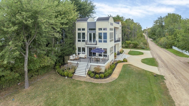 rear view of house with a lawn, a wooden deck, and a balcony