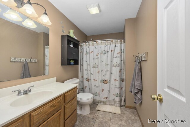 bathroom with a shower with curtain, vanity, toilet, and tile patterned floors