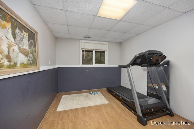 exercise area with a paneled ceiling and hardwood / wood-style floors