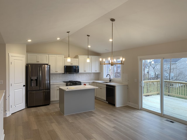 kitchen featuring stainless steel appliances, light countertops, visible vents, vaulted ceiling, and a sink