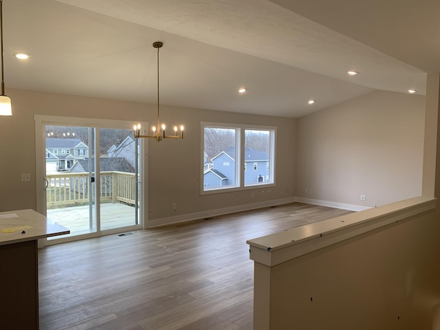 unfurnished dining area featuring a healthy amount of sunlight, vaulted ceiling, light wood-style flooring, and baseboards