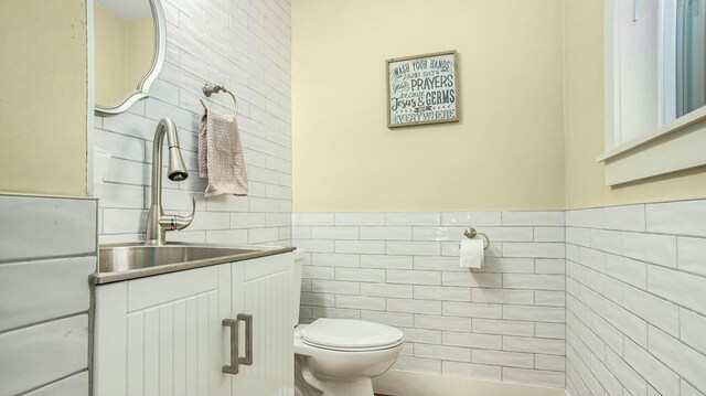 bathroom with vanity, toilet, and tile walls