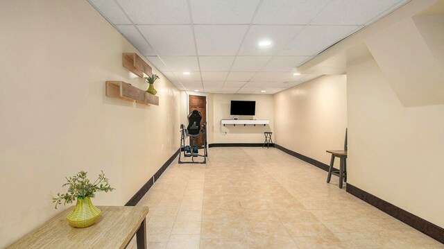 corridor with a paneled ceiling and light tile patterned flooring