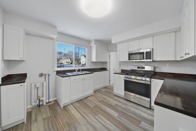 kitchen with sink, white cabinets, light hardwood / wood-style flooring, and appliances with stainless steel finishes