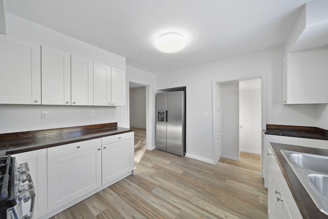 kitchen with white cabinets, stainless steel fridge, sink, and range