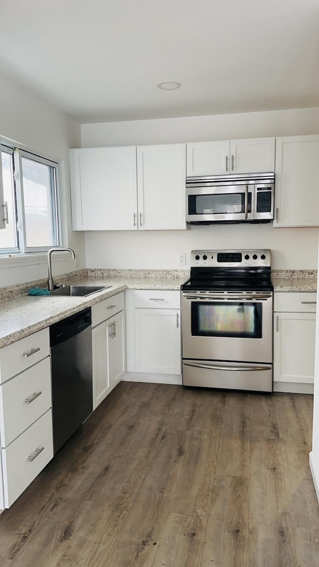 kitchen with white cabinets, dark wood-type flooring, appliances with stainless steel finishes, and sink