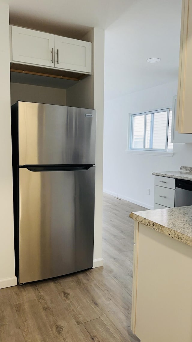 kitchen with stainless steel appliances, light wood-type flooring, and white cabinets