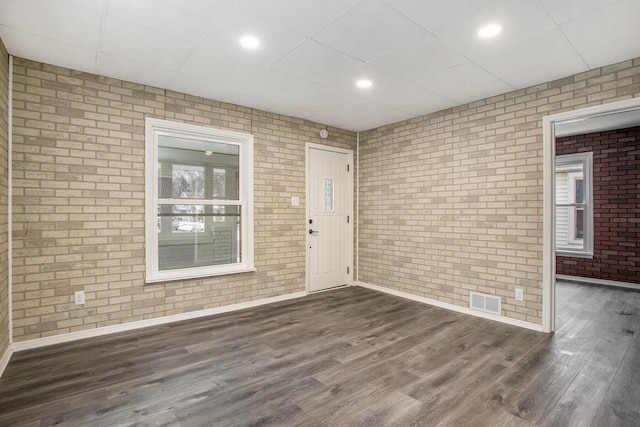 interior space with dark wood-type flooring and brick wall