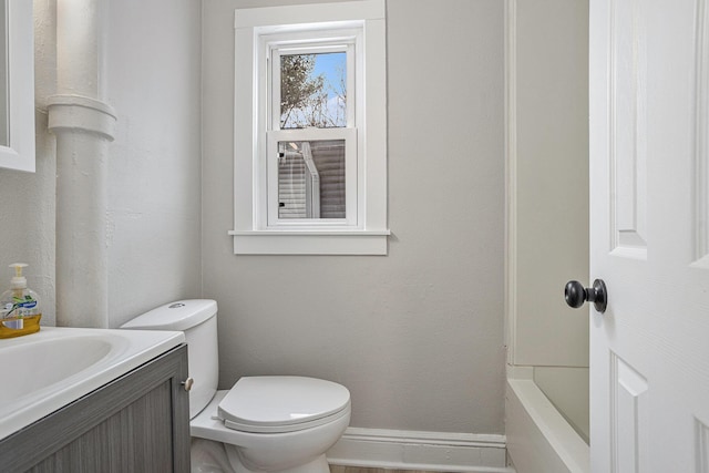 bathroom featuring vanity, a bathtub, and toilet