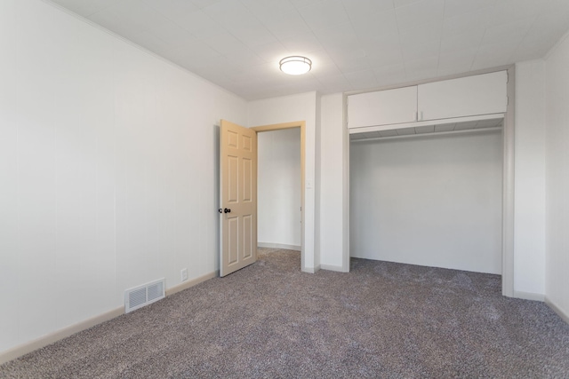 unfurnished bedroom featuring dark carpet and a closet