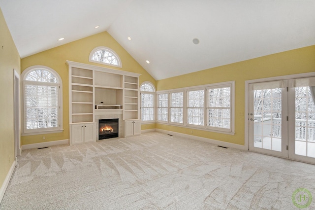 unfurnished living room featuring a tiled fireplace, light colored carpet, and high vaulted ceiling