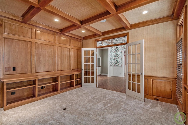 carpeted spare room with coffered ceiling, beam ceiling, and french doors