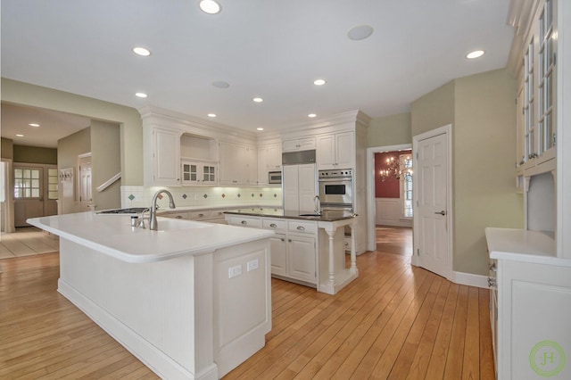 kitchen with sink, white cabinetry, light hardwood / wood-style flooring, appliances with stainless steel finishes, and a large island