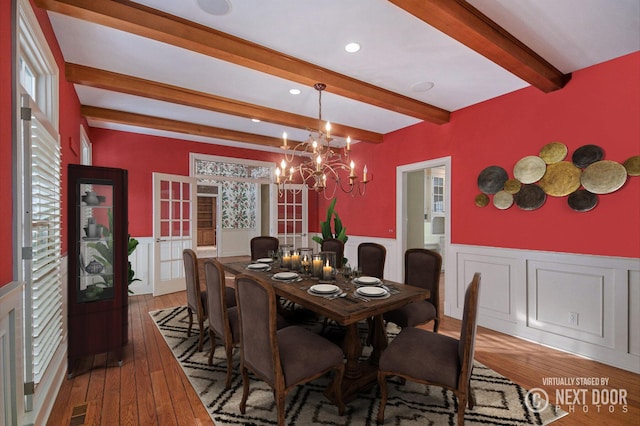 dining space featuring beamed ceiling, wood-type flooring, and a notable chandelier