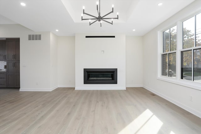 unfurnished living room featuring a chandelier and light wood-type flooring