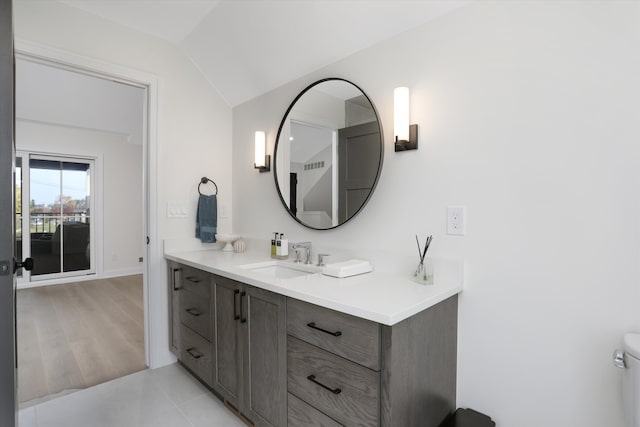 bathroom with tile patterned floors, vanity, vaulted ceiling, and toilet