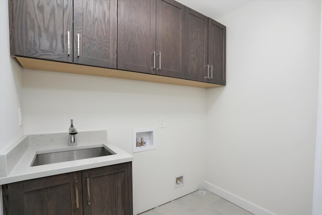 clothes washing area featuring cabinets, sink, light tile patterned floors, and washer hookup