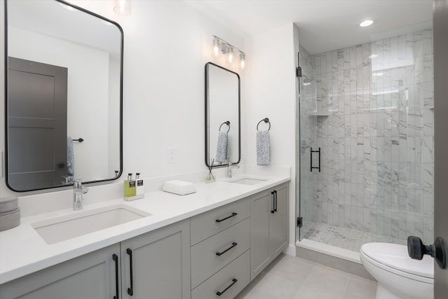 bathroom with tile patterned floors, vanity, a shower with shower door, and toilet