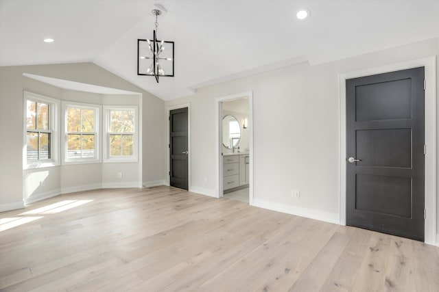 interior space with ensuite bathroom, vaulted ceiling, a chandelier, and light hardwood / wood-style flooring