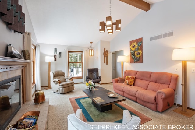 carpeted living room with a notable chandelier, lofted ceiling with beams, and a tile fireplace