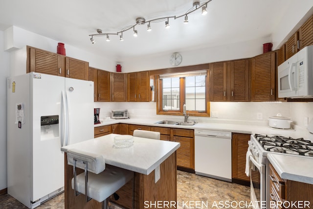 kitchen with a breakfast bar area, sink, a kitchen island, and white appliances