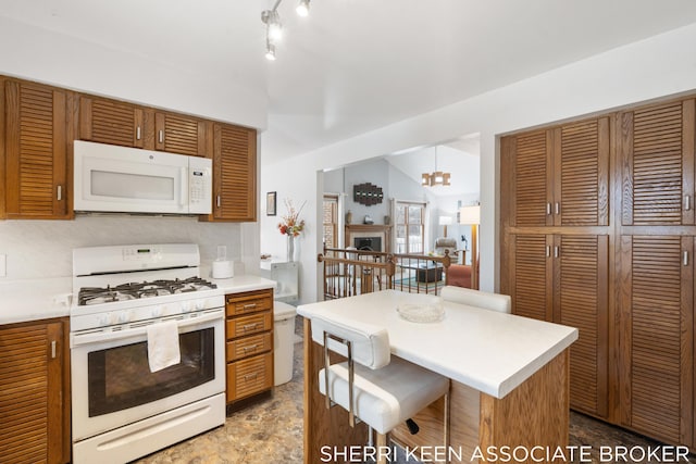 kitchen with white appliances, tasteful backsplash, a notable chandelier, a kitchen island, and a breakfast bar area