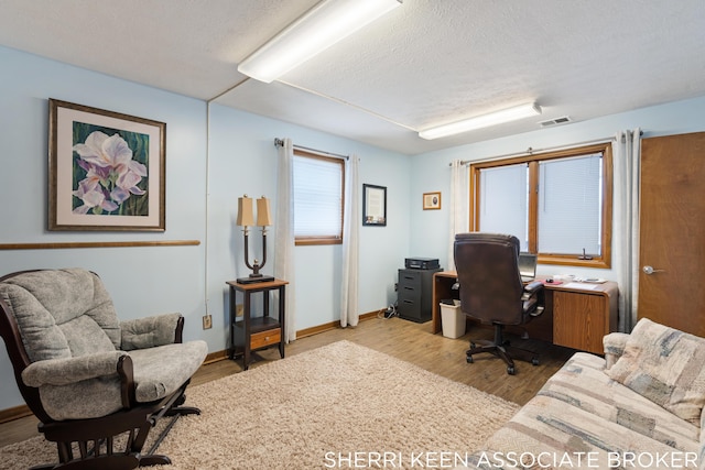 office area with light wood-type flooring and a textured ceiling