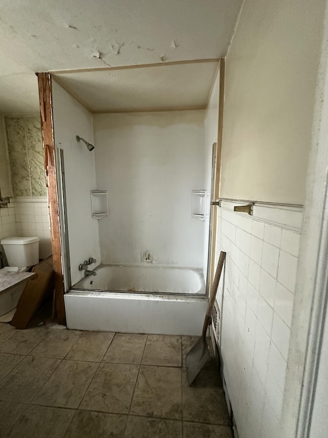 bathroom with tile patterned floors, shower / bathing tub combination, tile walls, and toilet