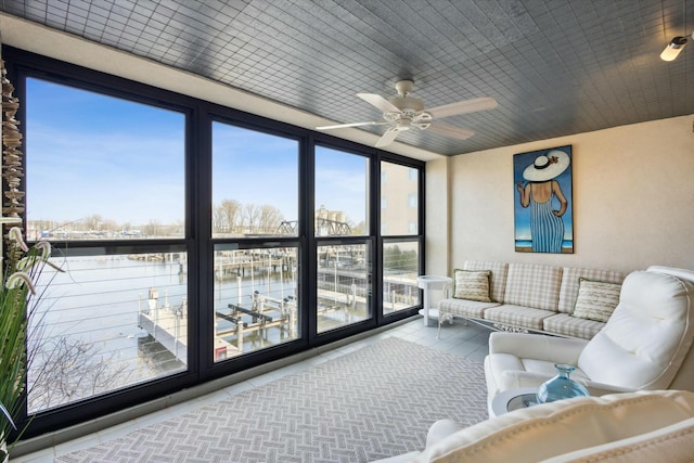 sunroom / solarium featuring a water view and ceiling fan