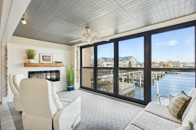 sunroom / solarium with ceiling fan and a water view