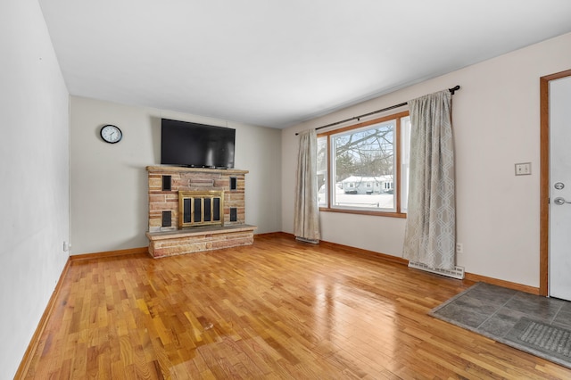 unfurnished living room with a fireplace, baseboards, and wood finished floors