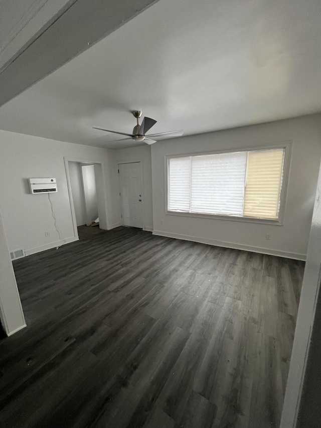 empty room with dark wood-type flooring, a wall mounted air conditioner, and ceiling fan