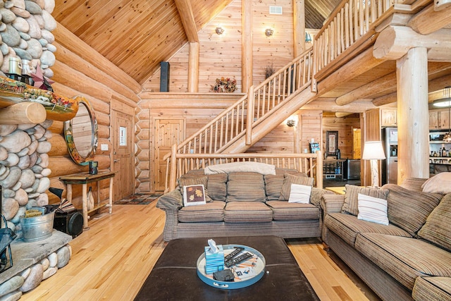 living room featuring rustic walls, light hardwood / wood-style floors, high vaulted ceiling, wooden ceiling, and beamed ceiling