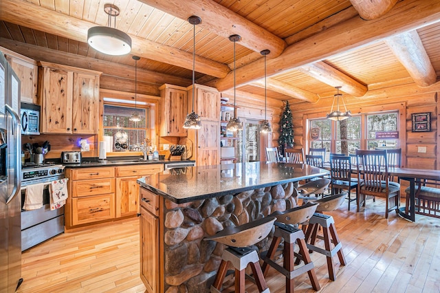 kitchen featuring pendant lighting, rustic walls, stainless steel appliances, wood ceiling, and a kitchen island