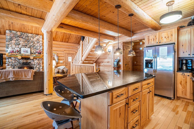 kitchen featuring log walls, a kitchen island, stainless steel fridge, and a kitchen bar